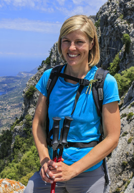Bild på blond kvinna i blå t-shirt som poserar på en bergsstig.shirt o