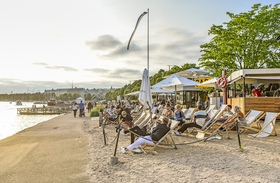 strandbild med människor i solstolar och flera barer/serveringar.